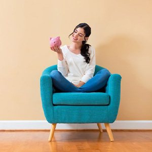 Woman sitting on her sofa admiring her piggy bank