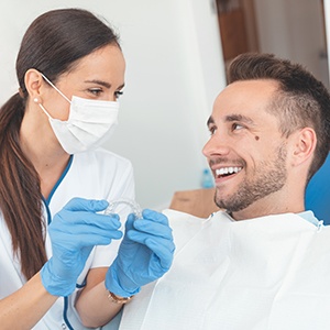 A dentist showing Invisalign aligners to her young male patient 