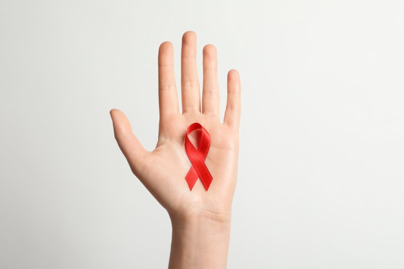 A hand holding a ribbon that symbolizes Oral Cancer Awareness Month